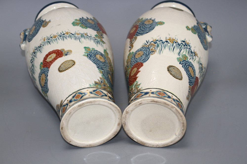 A pair of Satsuma vases, decorated with chrysanthemums, irises and storks, with beast head lug handles, height 31cm